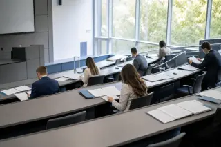 Students in a bright university amphitheater studying administrative documents during a professional training session, with a calm and organized atmosphere, neutral institutional colors, and no identifiable faces.