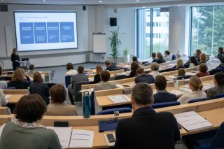 Training amphitheater in a modern healthcare institution with students and educators, neutral colors, morning light, people with non-identifiable faces engaged in learning.